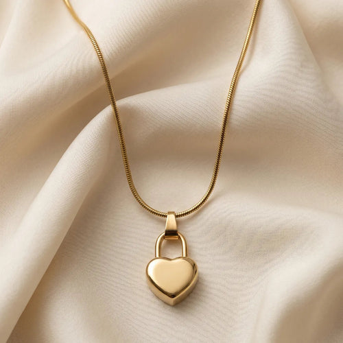 Gold heart-shaped padlock necklace on a beige fabric background