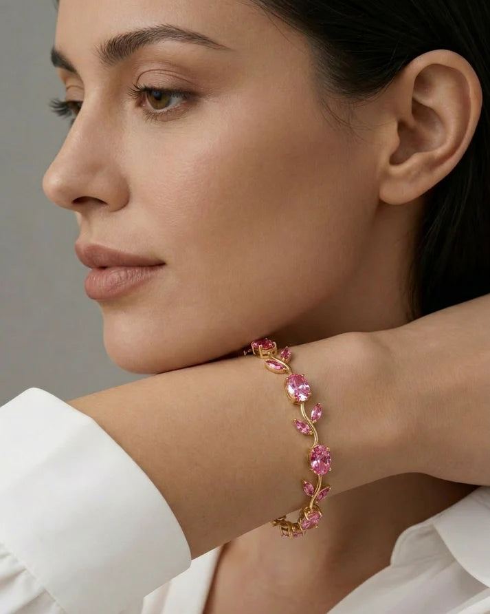 Close-up of a woman wearing a gold bracelet with crystals on a neutral background