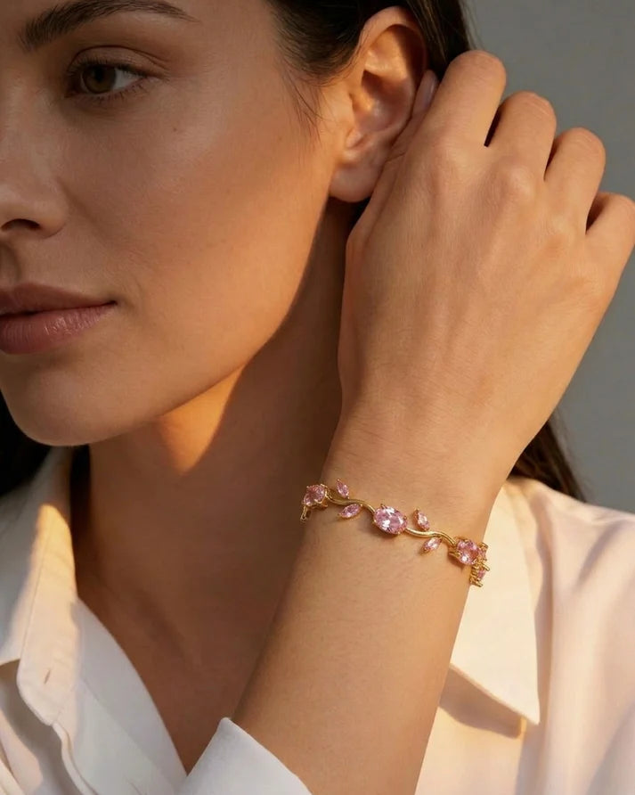 Woman wearing a gold bracelet with clear stones, touching her hair.