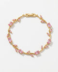 A gold vine bracelet adorned with marquise-cut pink gemstones, displayed on a clean white background.