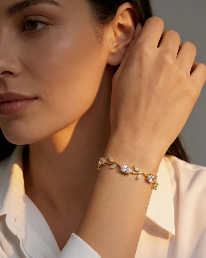 Woman wearing a gold bracelet with clear stones, touching her hair.